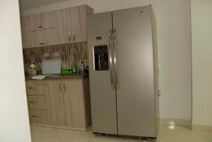 a stainless steel refrigerator in a kitchen with wooden cabinets at Comfortable Itagüí Stay in Itagüí