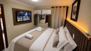 a bedroom with a large white bed with a tv on the wall at Solar de Pipa Vip Confort - Spa Hidro Flat in Pipa +103 photos