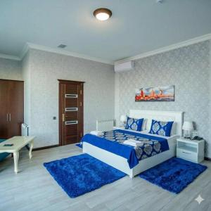 a bedroom with a blue and white bed and blue rugs at Caspian Seaside Hotel in Sumqayıt