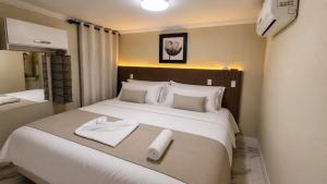 a bedroom with a large white bed with towels on it at Solar de Pipa Vip Confort - Spa Hidro Flat in Pipa