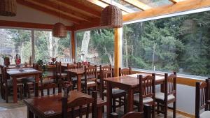 a restaurant with wooden tables and chairs and large windows at Hosteria Lekun Lekun in Villa La Angostura