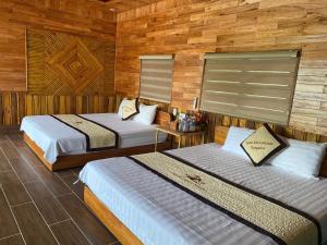 two beds in a room with wooden walls at Xuan Son Lakeside Bungalow in Ninh Binh