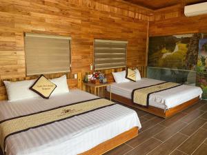 two beds in a room with wooden walls at Xuan Son Lakeside Bungalow in Ninh Binh