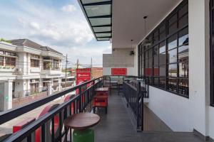 a balcony with tables and chairs on a building at RedDoorz Plus @ Doorman Guest House in Bandung