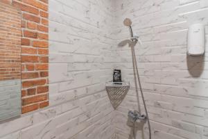 a white brick wall with a shower in a bathroom at RedDoorz Plus @ Doorman Guest House in Bandung +27 photos