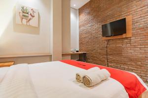 a bedroom with a bed and a tv on a brick wall at RedDoorz Plus @ Doorman Guest House in Bandung