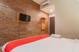a bedroom with a bed and a brick wall at RedDoorz Plus @ Doorman Guest House in Bandung