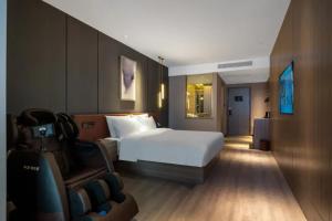 a hotel room with a bed and a chair at Orange Hotel Xiamen City Hall in Xiamen