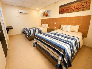a hotel room with two beds with striped sheets at Hotel Tulipanes in Villahermosa +4 photos
