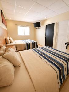 a hotel room with two beds and a tv at Hotel Tulipanes in Villahermosa