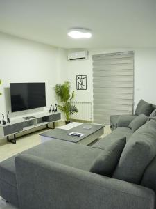 a living room with a couch and a flat screen tv at Casa Dunia - 2 BR Open Sea View Apartment in Sahl ‘Almā