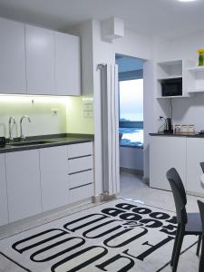 a kitchen with white cabinets and a table and a kitchen rug at Casa Dunia - 2 BR Open Sea View Apartment in Sahl ‘Almā