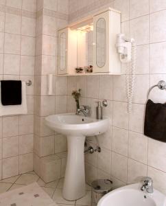 a white bathroom with a sink and a toilet at Hotel Rajna in Starigrad