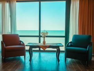 a living room with a table and two chairs and a window at Caspian Seaside Hotel in Sumqayıt