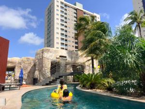 two people riding on an inner tube in a swimming pool at Apartamento em Salinas Premium Resort in Salinópolis