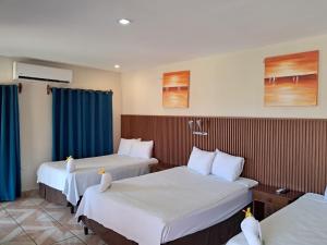 a hotel room with three beds and blue curtains at Hotel Miraflores in El Cuco +72 photos