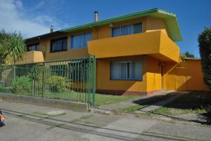 una casa amarilla con una valla delante de ella en La Casa Toesca, en Valdivia