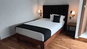 ein Schlafzimmer mit einem großen weißen Bett mit schwarzem Kopfteil in der Unterkunft Hotel Sicilia, Aguascalientes in Aguascalientes