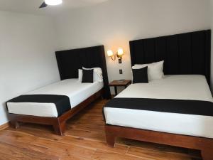 zwei Betten in einem Hotelzimmer mit Röcken in der Unterkunft Hotel Sicilia, Aguascalientes in Aguascalientes