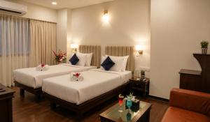 a hotel room with two beds and a couch at Ello Hotels in Bangalore