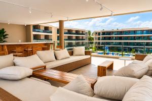 a living room with white furniture and a large window at FLAT RESORT LUXO MALIA 215E- Porto de Galinhas - Muro Alto in Porto De Galinhas