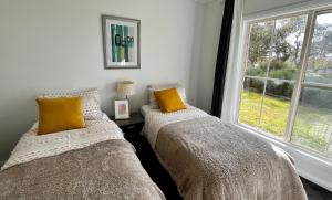 two beds sitting next to a window in a bedroom at Winterwood Lodge - 6mins Jindabyne -Pets Allow-Floor Heating Winter-Swimming Pool Summer in Moonbah