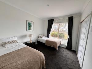 a bedroom with two beds and a window at Winterwood Lodge - 6mins Jindabyne -Pets Allow-Floor Heating Winter-Swimming Pool Summer in Moonbah