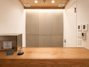 a room with a door and a clock on a wooden floor at Ishigaki Guesthouse HIVE in Ishigaki Island