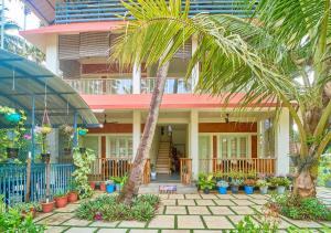 a house with palm trees and plants in front of it at Ocean View Beach Villa Varkala by VOYE HOMES in Varkala