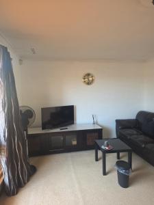 a living room with a couch and a flat screen tv at Nice quite stay in Perth