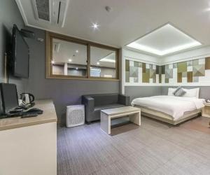 a bedroom with a bed and a desk and a tv at W Hotel in Yangsan