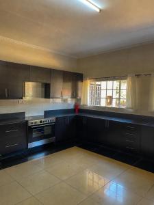 a large kitchen with black cabinets and a window at Royal Homes in Lilongwe