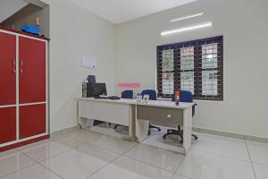 an empty office with a desk and blue chairs at Hotel O Skywind in Trivandrum