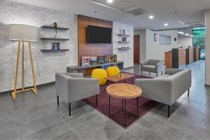 a lobby with chairs and a table and a tv at City Express by Marriott Monterrey Aeropuerto in Monterrey