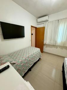 a bedroom with a bed and a flat screen tv at Sobrado Flamboyant in Goiânia