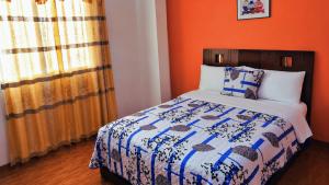 a bedroom with a bed with an orange wall at Hostal Mariscal Sucre in Tababela
