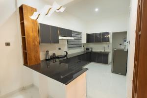a kitchen with black counter tops and a refrigerator at Rivera Residency , Kazhakuttom in Murukkumpuzha +4 photos