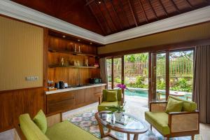 a living room with green chairs and a table at Arkamara Dijiwa Ubud in Ubud