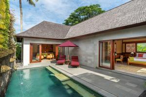 a house with a swimming pool with chairs and a table at Arkamara Dijiwa Ubud in Ubud