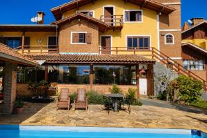 a house with a swimming pool in front of a house at Pousada Palma Chalés in Monte Verde +28 photos
