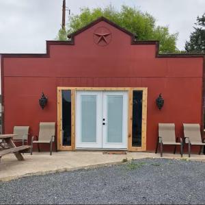 a red building with a white door and chairs at River Run Bo's Place in Kerrville +11 photos