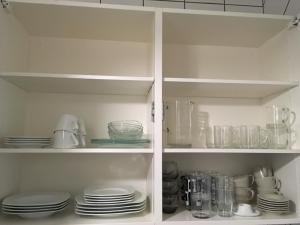 a white pantry with plates and dishes on shelves at Residence Luxurious Genève in Geneva