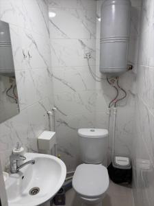 a white bathroom with a toilet and a sink at Hostel 1869 in Karakol