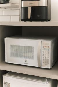 a microwave sitting on a shelf next to a toaster oven at 4-Studio Completo com Ar-Condicionado, TV e Lavanderia in Londrina
