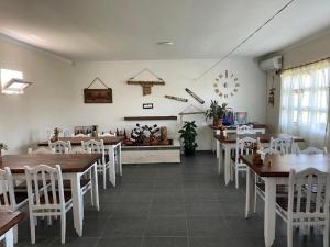 a dining room with wooden tables and white chairs at jibo in Grigoleti