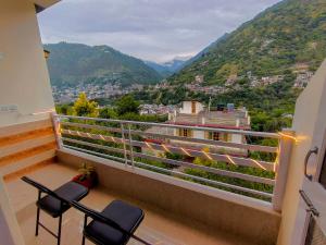 a balcony with two chairs and a view of mountains at Cedar Crest Homestay in Kulu