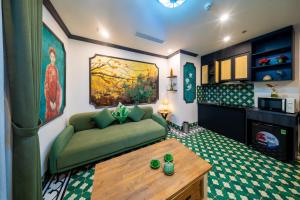 a living room with a green couch and a table at Nature Hotel and Spa Ha Noi in Hanoi
