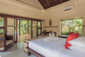 a bedroom with a large white bed with red pillows at Villa KaRo Pemuteran in Pemuteran