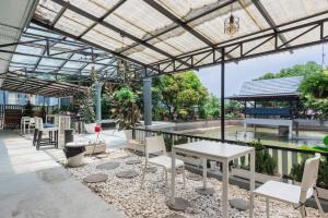 a patio with tables and chairs under a metal roof at BKK39 Airport Hotel in Lat Krabang