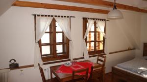 a dining room with a table and two windows at penzion Drevenica in Šumiac